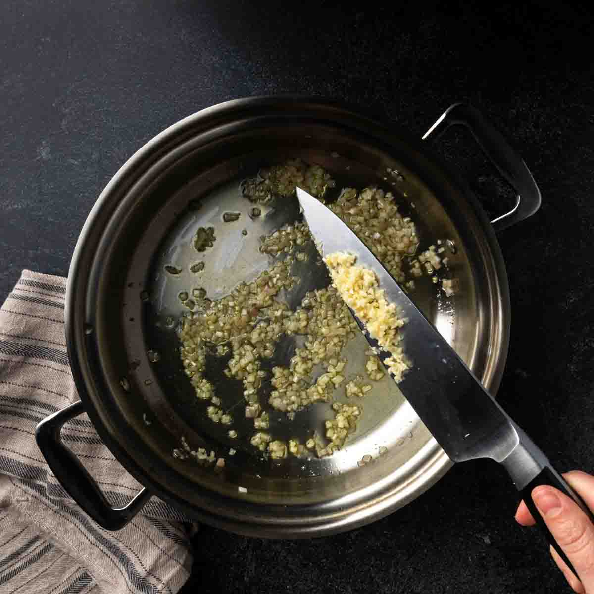 Adding minced garlic to the pan with the shallots.