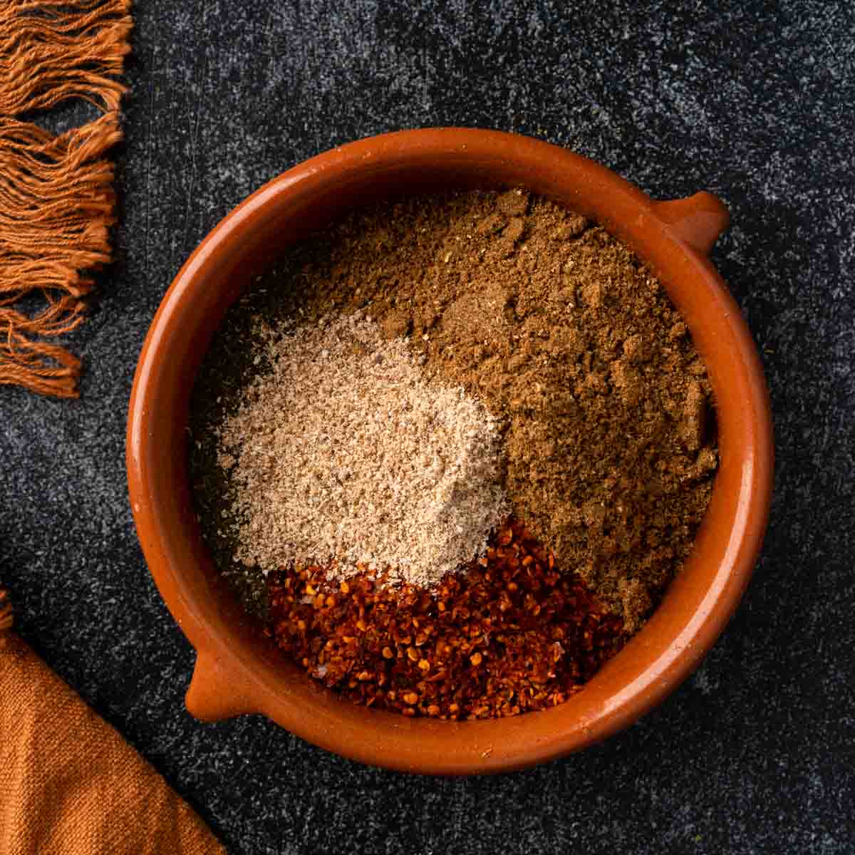 A dish full of piles of spices needed to make baharat.