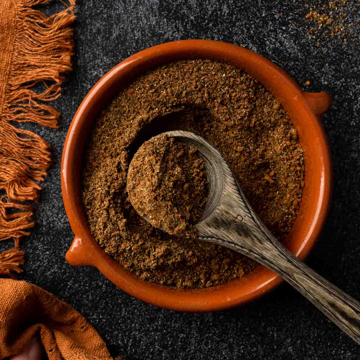 A dish of homemade baharat with a heaping wooden spoonful. 