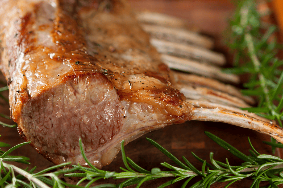 A stock image of roasted lamb rack and fresh rosemary.