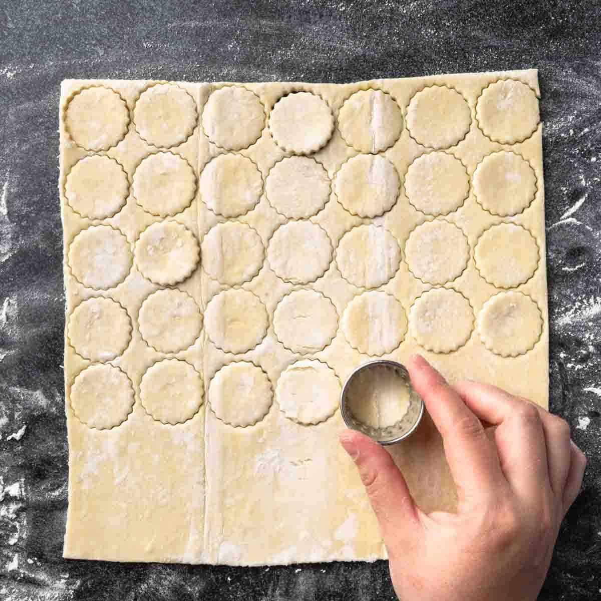 A sheet of puff pastry dough with several rows of small circles punched into it.