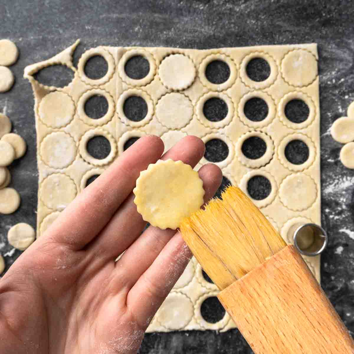 Brushing a tiny circle of puff pastry with egg wash.