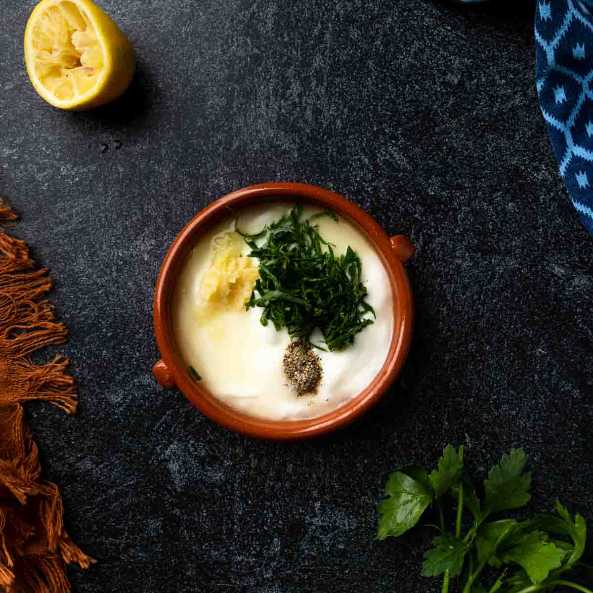 A bowl with yogurt and ingredients to flavor the yogurt sauce.