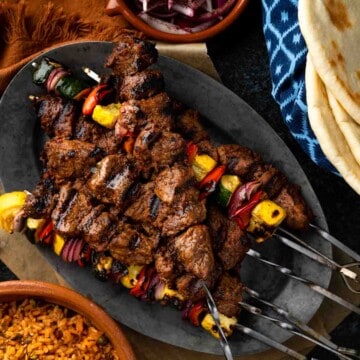 A close up image of Turkish lamb shish kebabs and grilled veggie skewers.