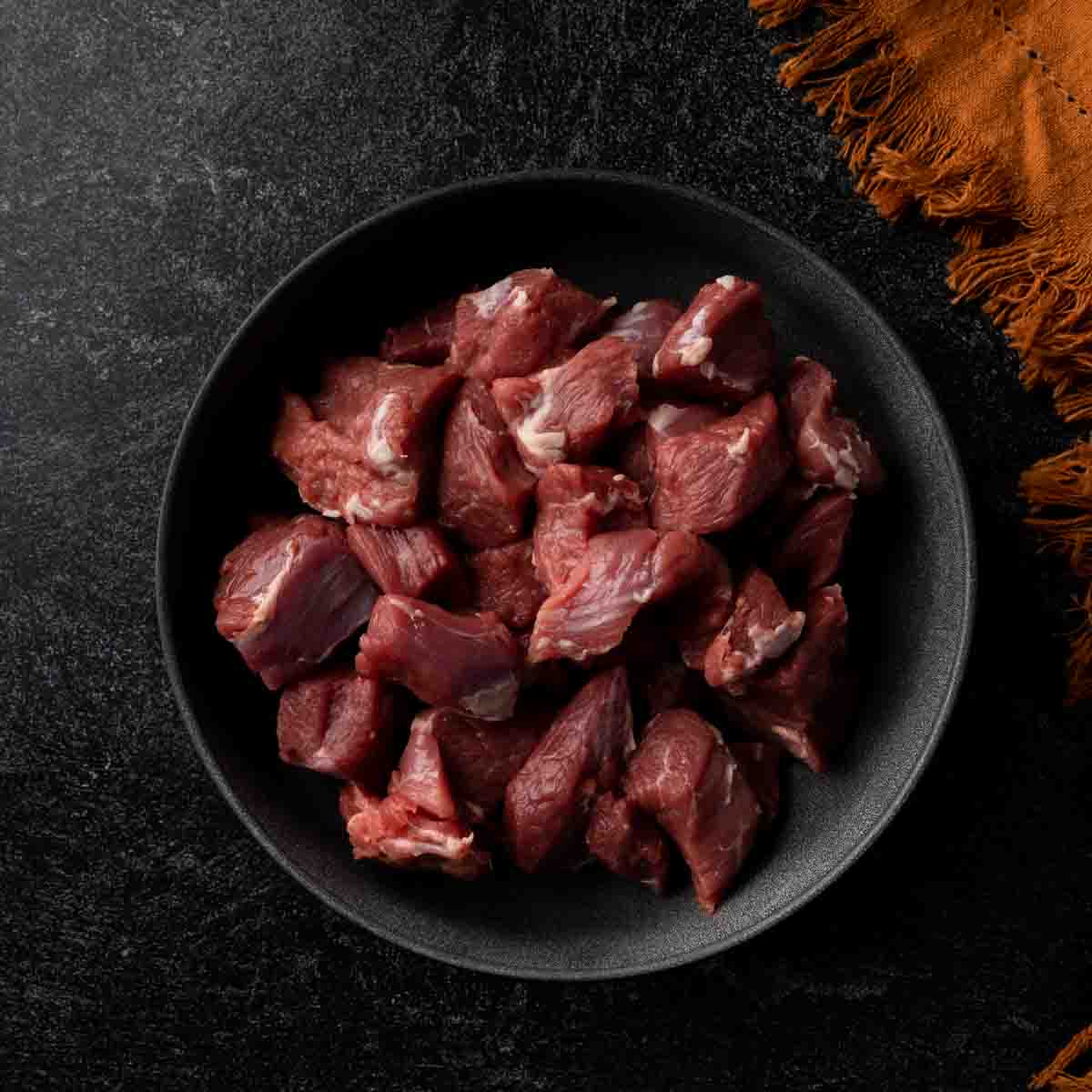 A bowl of trimmed and cubed lamb leg.