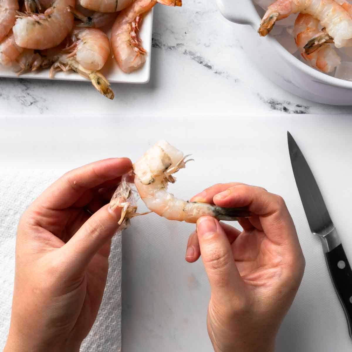 Pulling the shell off of the shrimp.