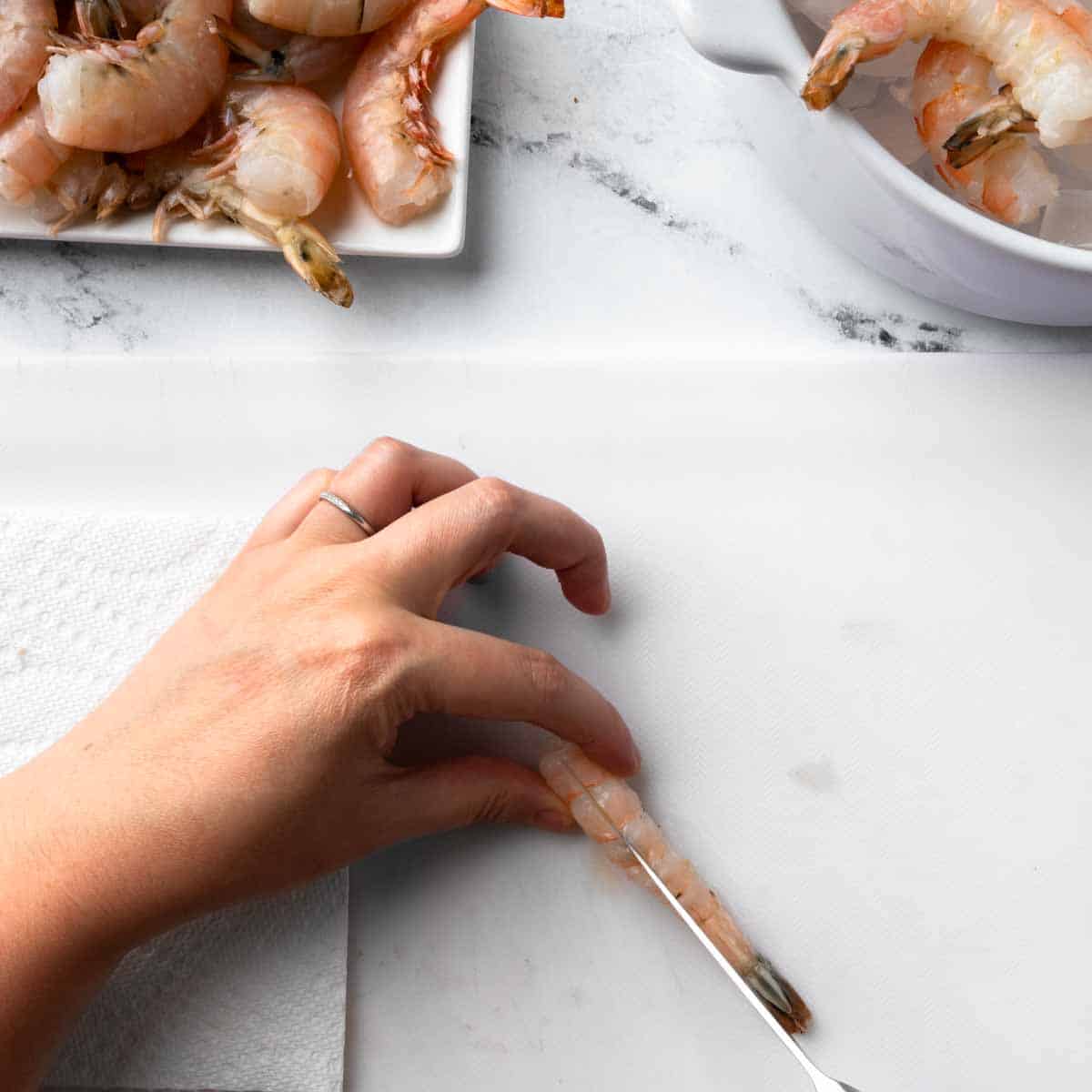 Using a paring knife to cut a slit along the shrimps back.