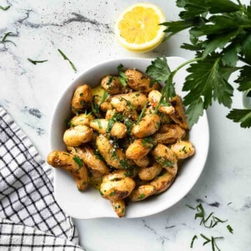 A dish of grilled fingerling potatoes with half a lemon and fresh parsley.