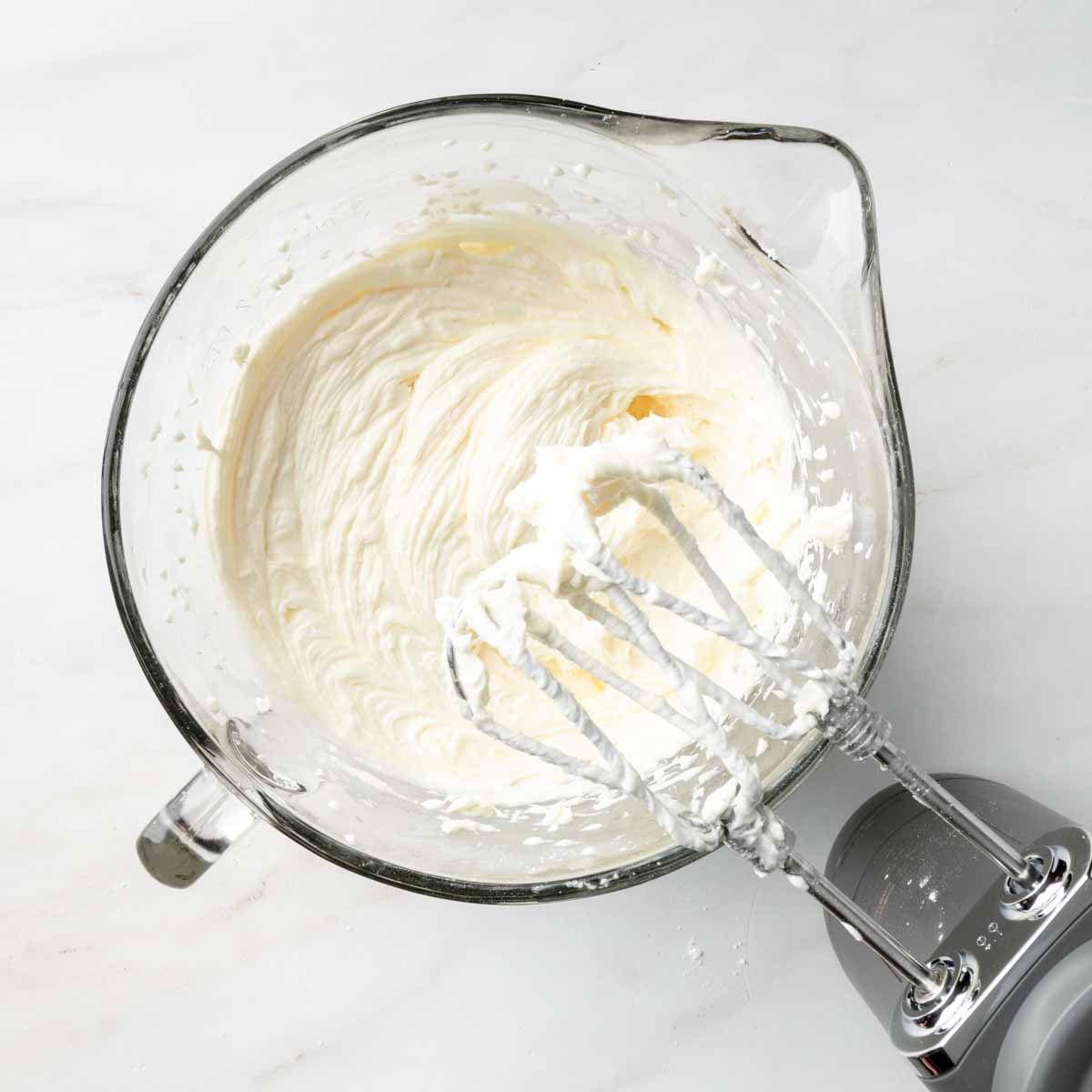 A mixing bowl with whipped cream cheese and icing sugar. 