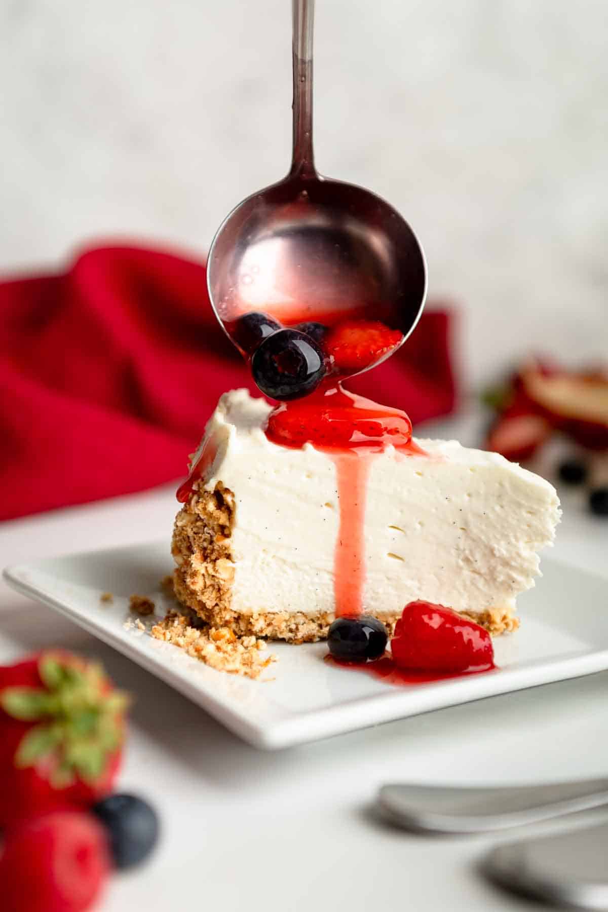 Pouring red, white and blue berry syrup over a pretty slice of vanilla pretzel cheesecake. 