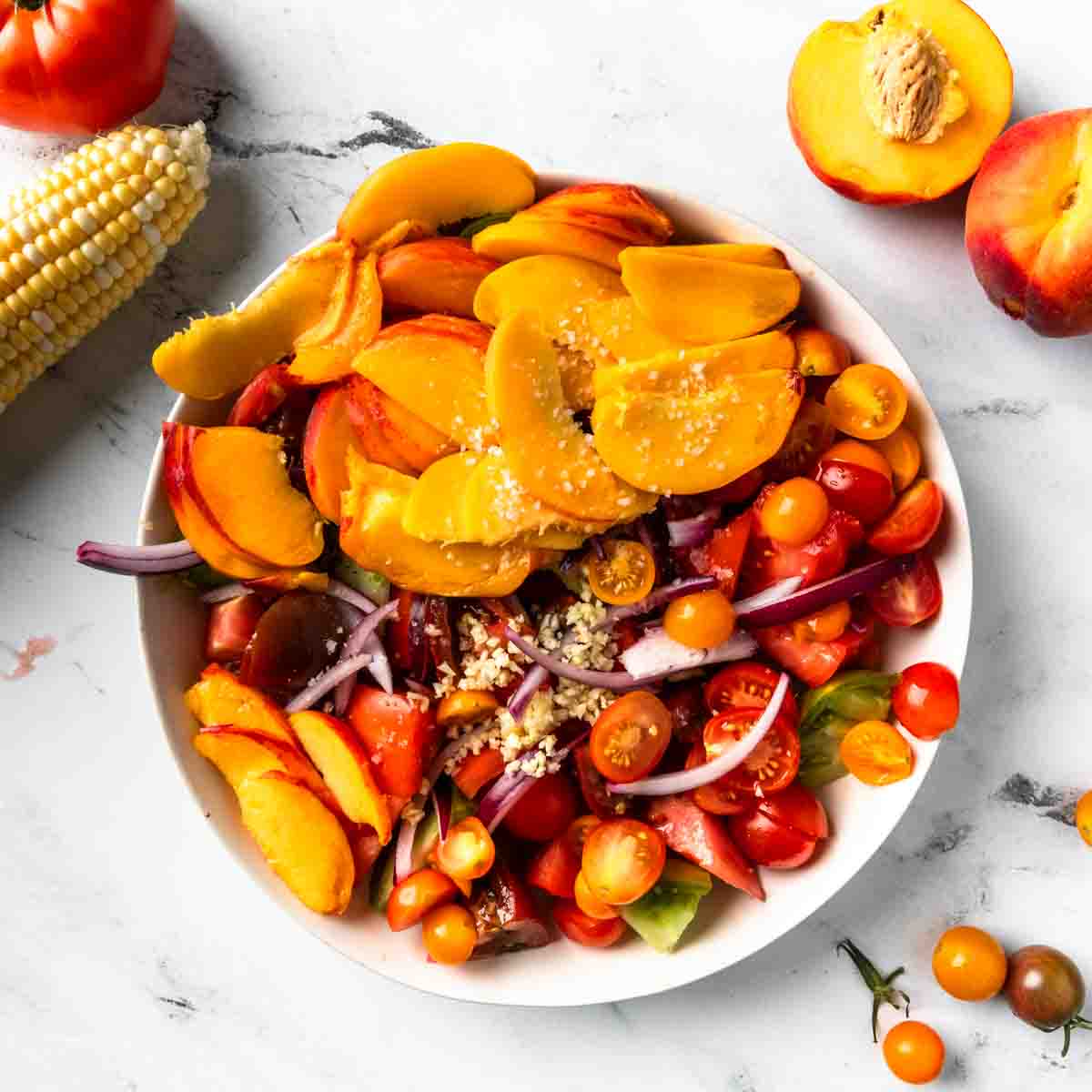 A bowl of all the produce needed to make peach panzanella salad. 