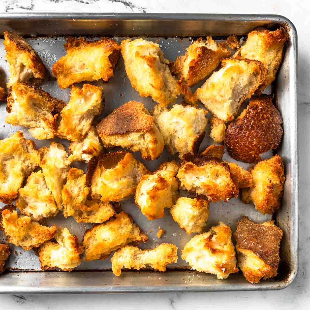 A sheet pan of golden olive oil toasted sourdough croutons.