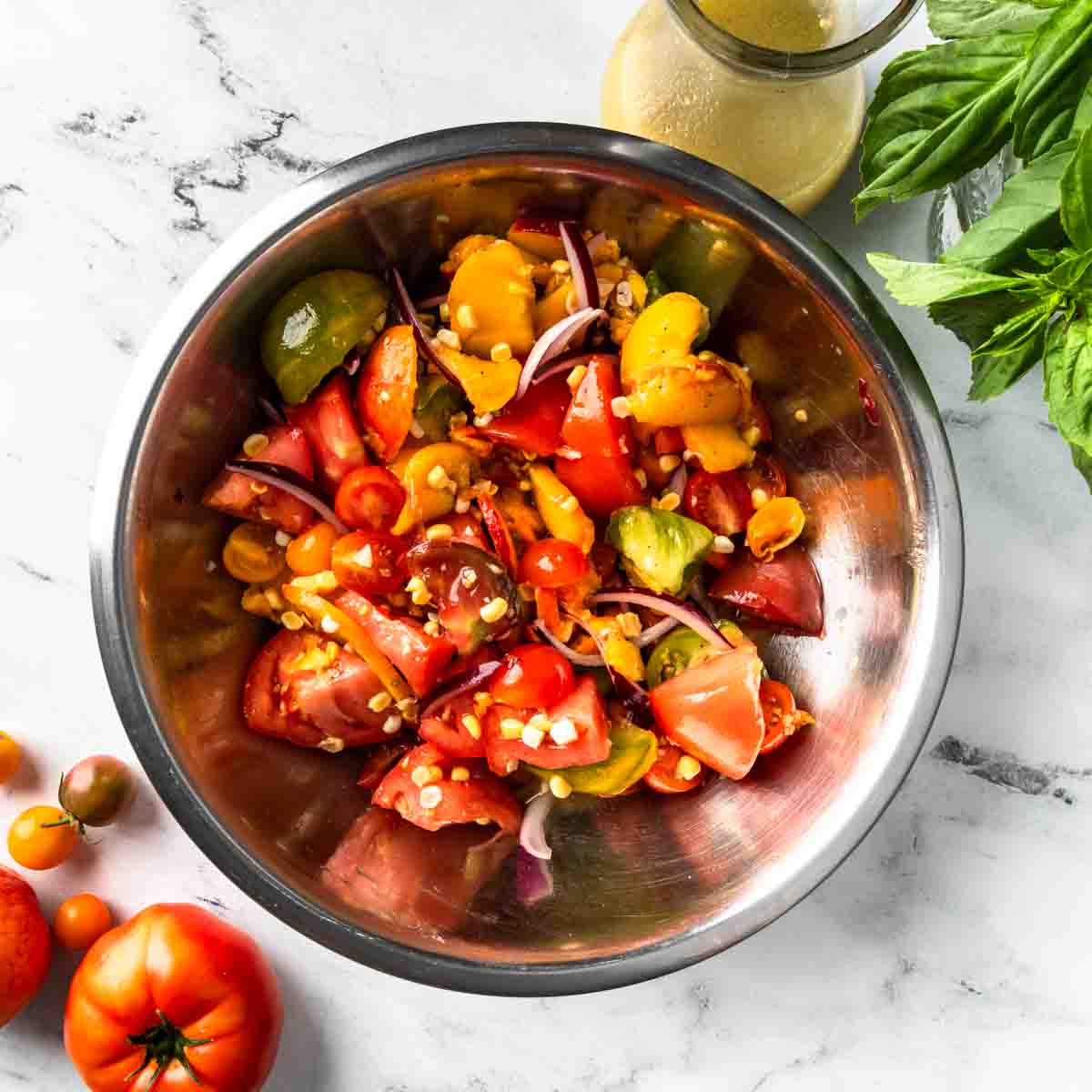 A bowl of panzanella produce marinating in garlic and white balsamic vinaigrette. 