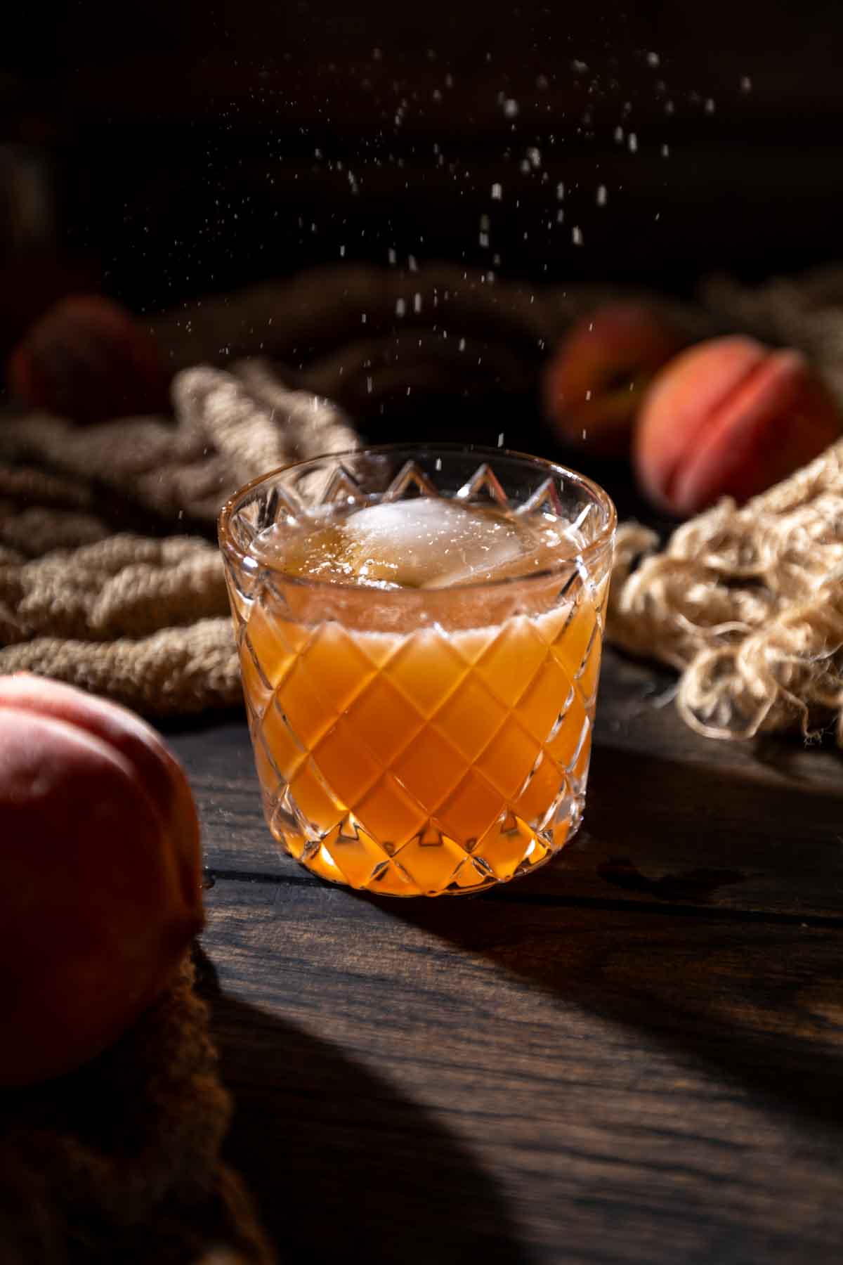 A dusting of freshly grated nutmeg falling over a peach pie cocktail. 