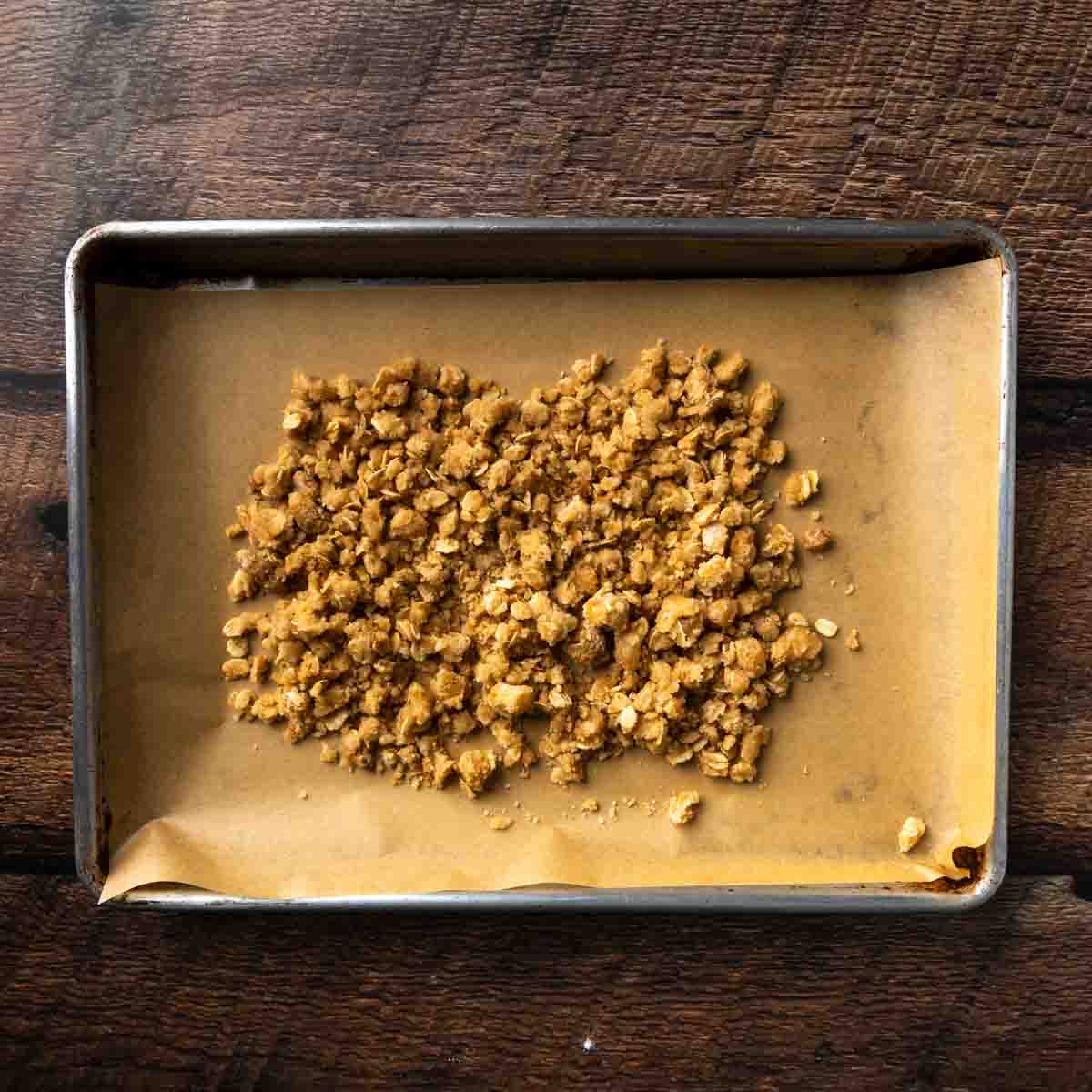 Crumbled oatmeal cookie dough scattered across a baking tray. 