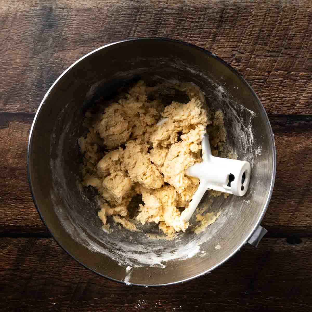 A mixer full of soft cookie dough clinging to the paddle attachment. 