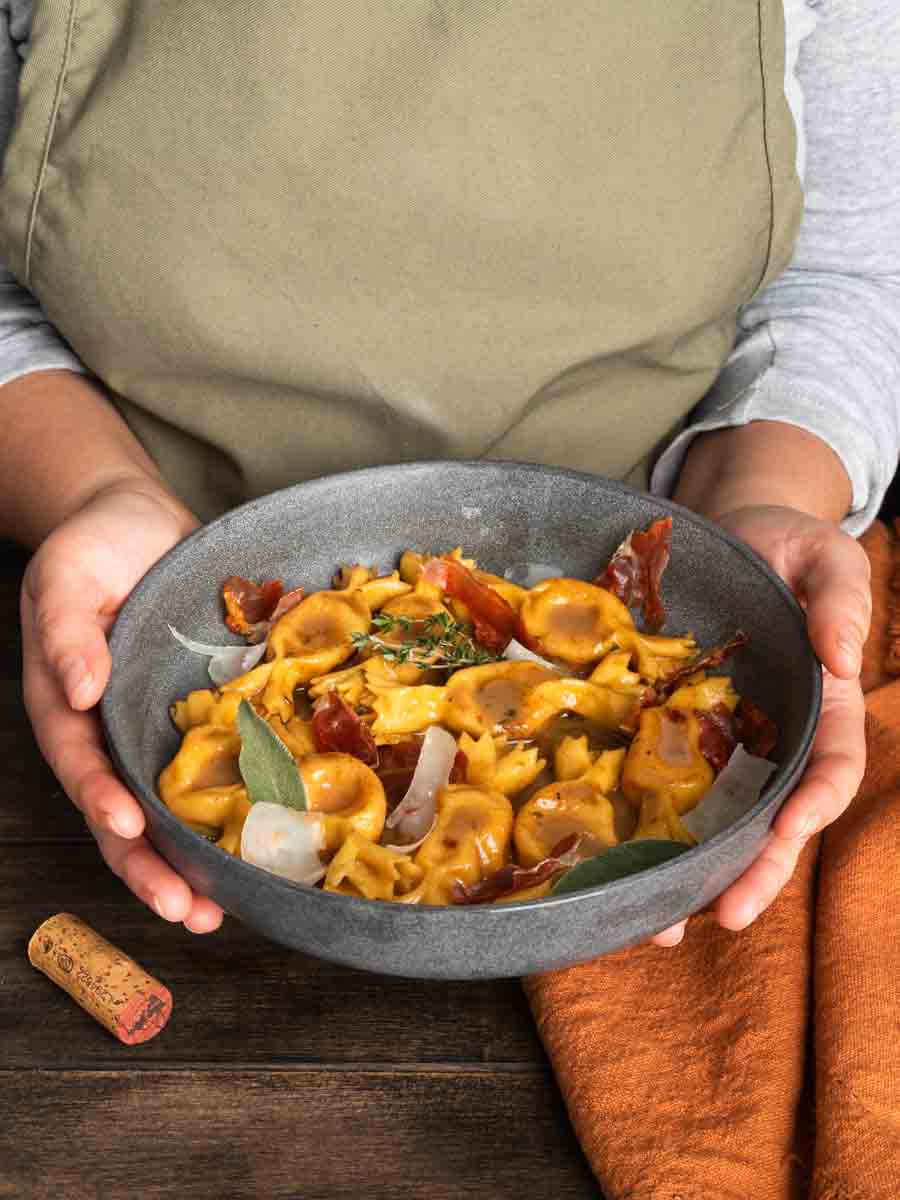 A bowl of sweet potato caramelle being held by someone in a sage apron.