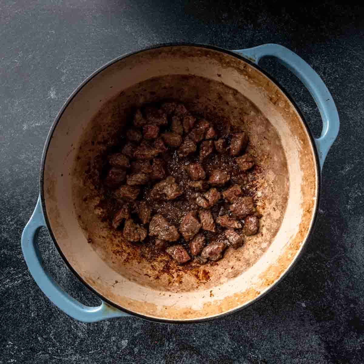 Searing beef cubes in a Dutch oven. 