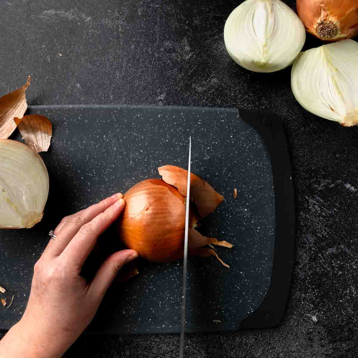 Cutting the bud end off of half an onion.