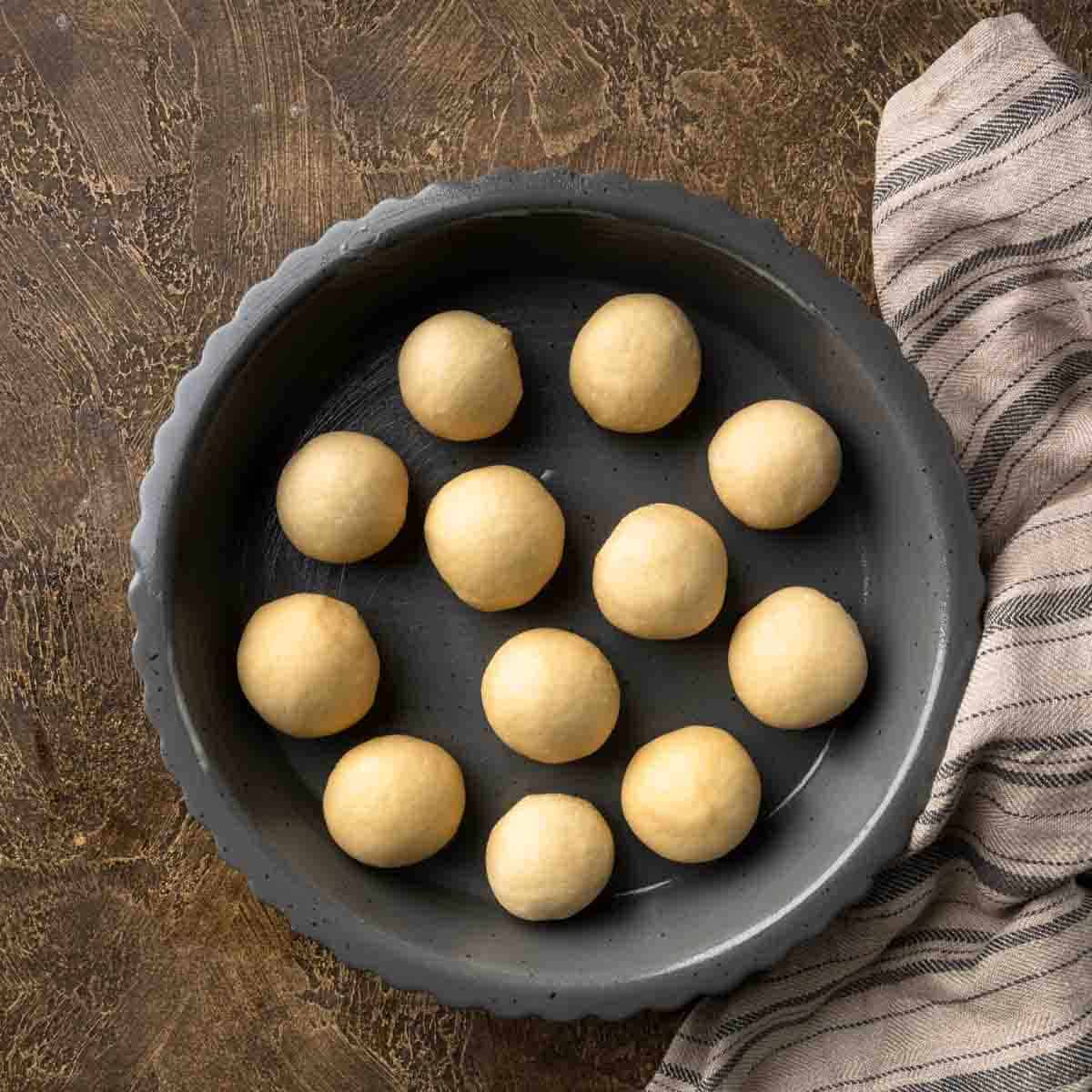 A round dish full of dough balls.