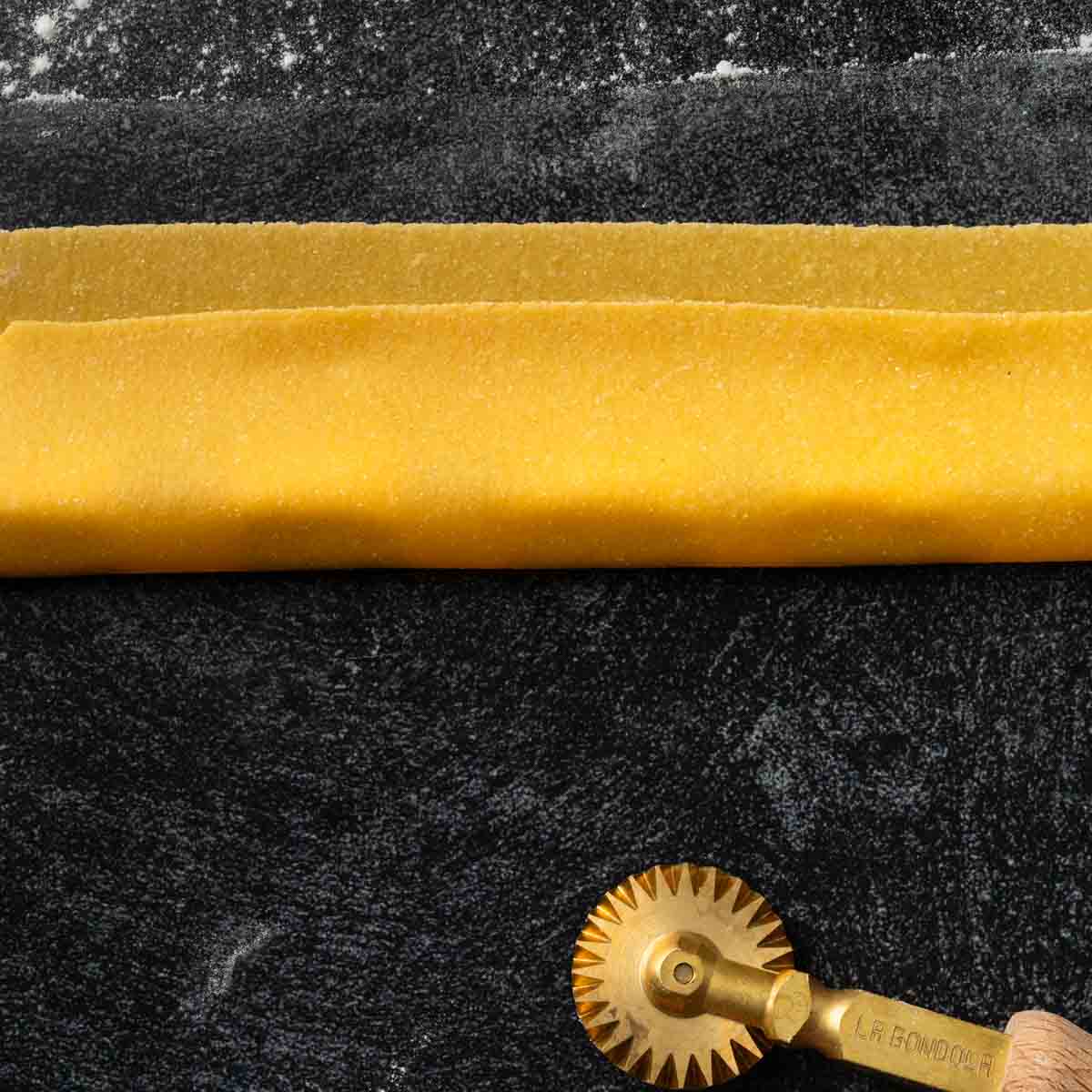 A sheet of pasta dough folded over dollops of ricotta filling.
